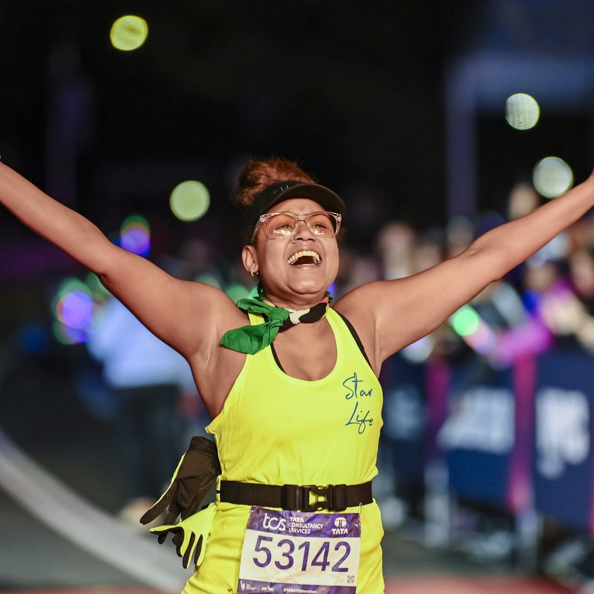 A final finisher crosses the finish line with her arms outstretched