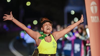A final finisher crosses the finish line with her arms outstretched