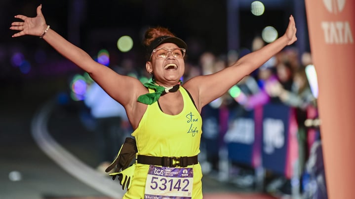 A final finisher crosses the finish line with her arms outstretched