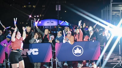 A female final finisher runs through the finish line with her arms up in the air