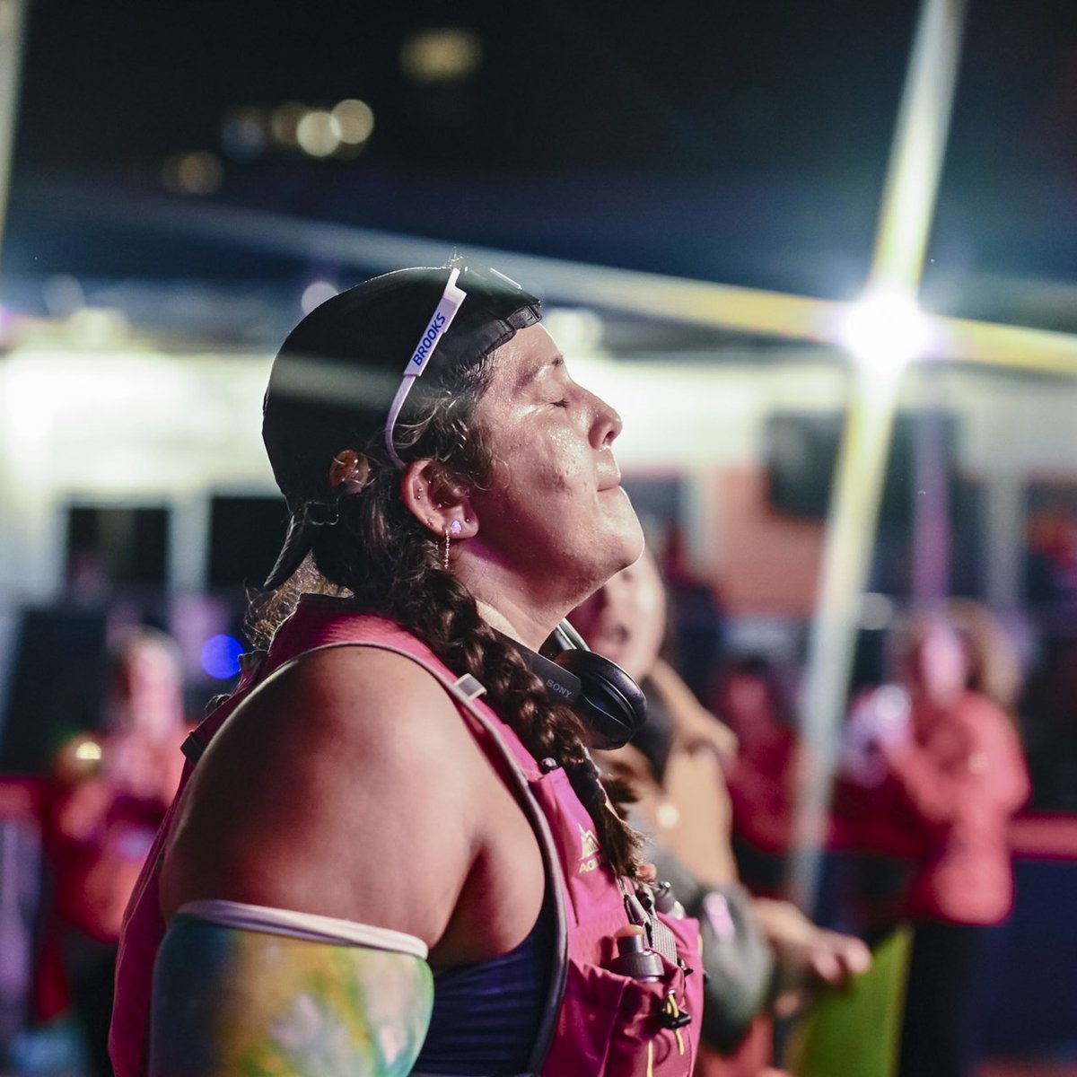 A woman crosses the finish line at night looks up and closes her eyes