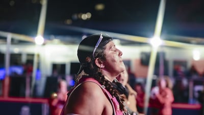 A woman crosses the finish line at night looks up and closes her eyes
