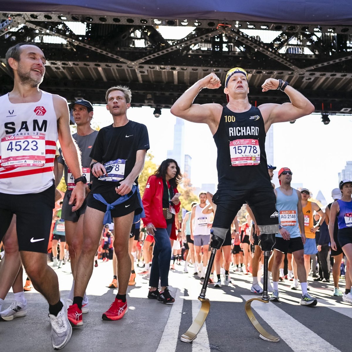 A runner with prosthetic legs flexes his bicep muscle at the finish line of the TCS New York City Marathon