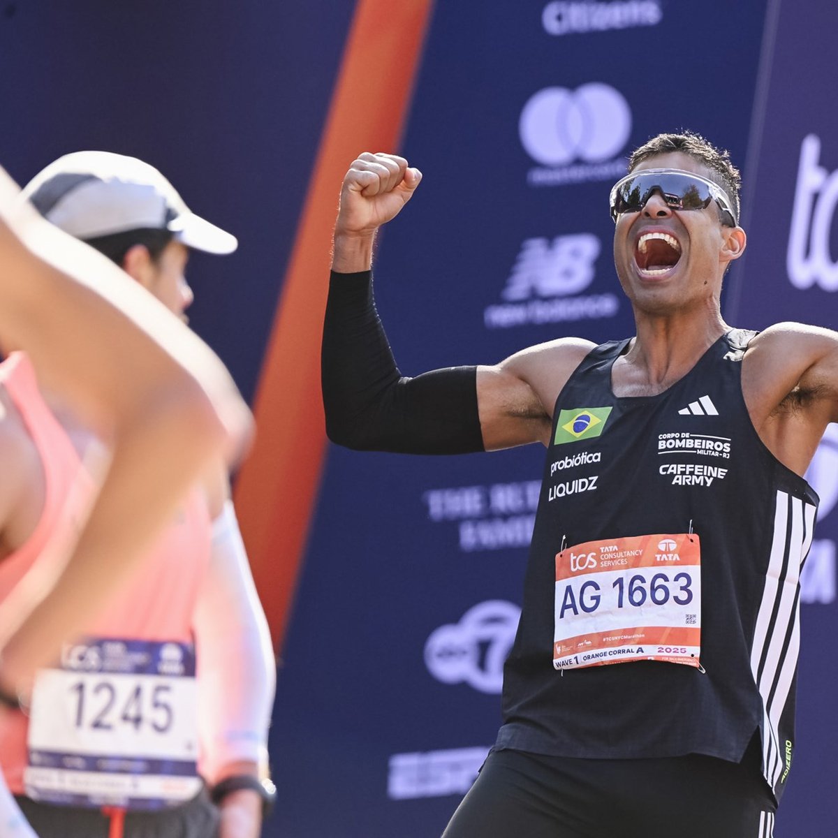 A man flexes his bicep muscles and screams with joy at the finish line of the TCS New York City Marathon