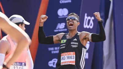 A man flexes his bicep muscles and screams with joy at the finish line of the TCS New York City Marathon