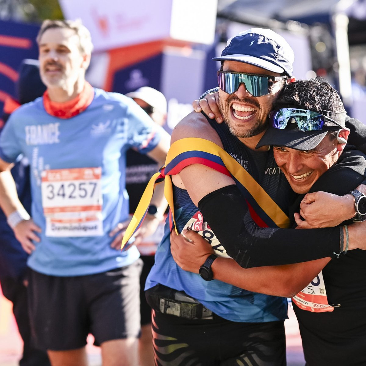 Two men embrace and smile at the finish line of the TCS New York City Marathon