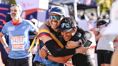 Two men embrace and smile at the finish line of the TCS New York City Marathon