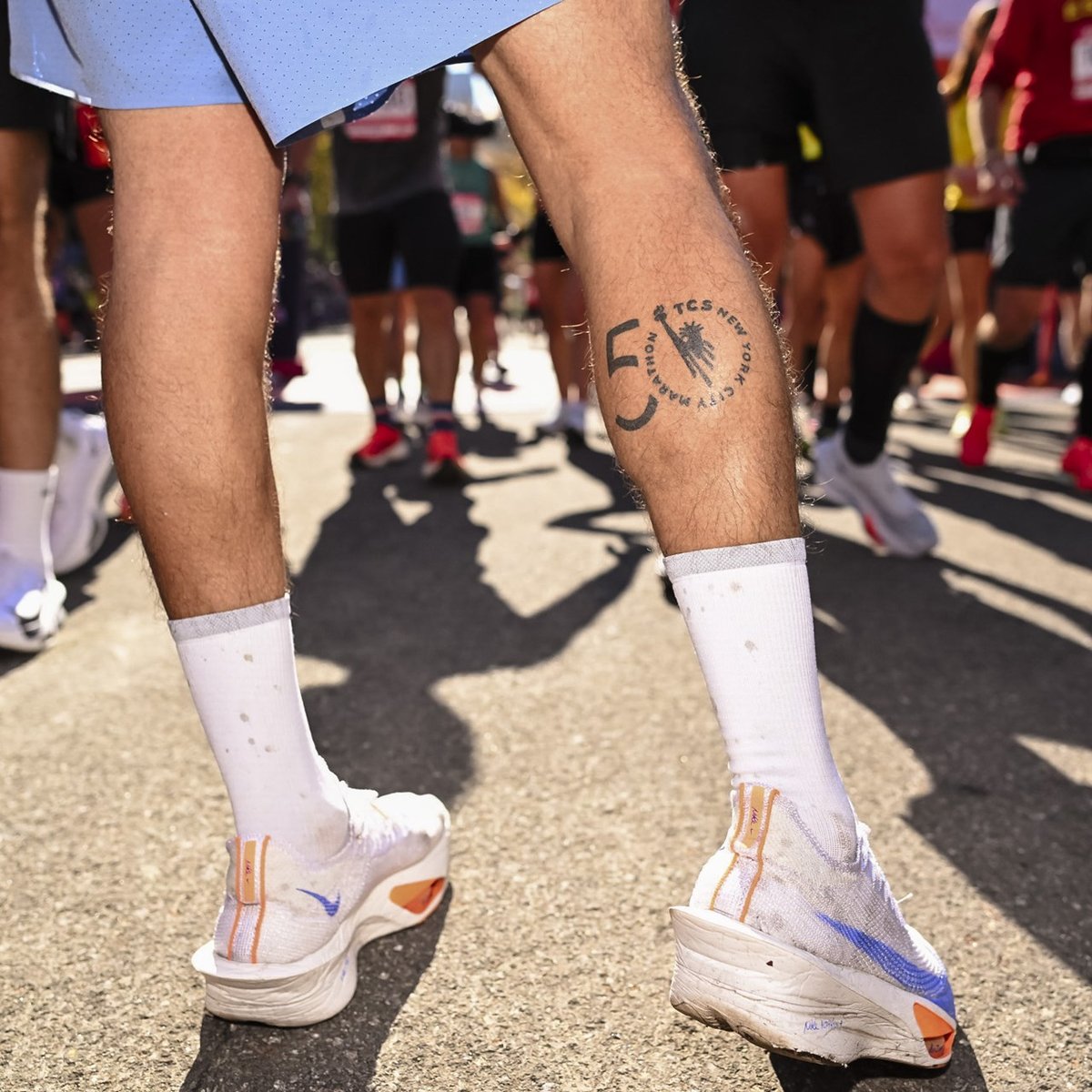 A man's legs with a 50th TCS New York City Marathon on his right calf