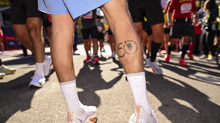 A man's legs with a 50th TCS New York City Marathon on his right calf