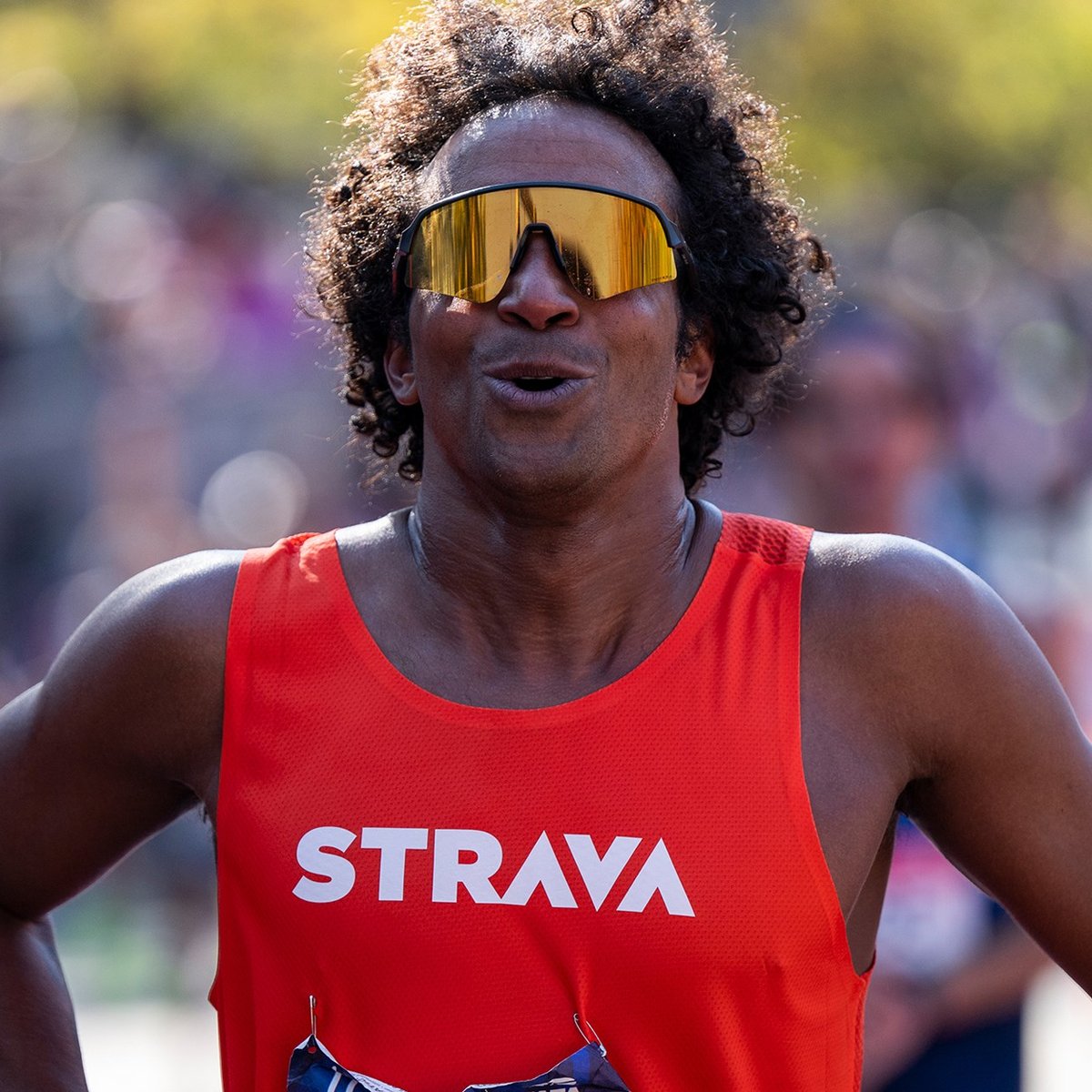 A man in a Strava singlet and sunglasses takes a deep breath