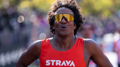 A man in a Strava singlet and sunglasses takes a deep breath