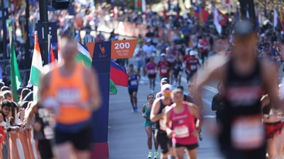 The 200 meters to go sign with some blurry and some in focus runners and spectators in the background