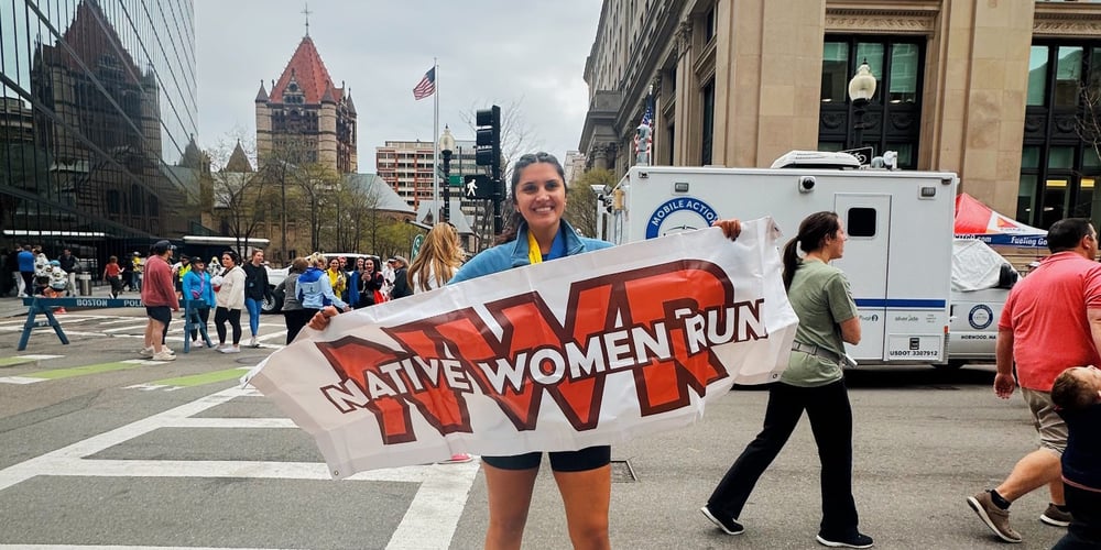 Hope Pinsonault holding up a Native Women Run banner.