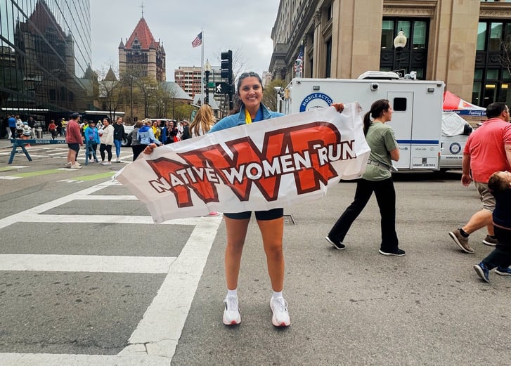 Hope Pinsonault holding up a Native Women Run banner.