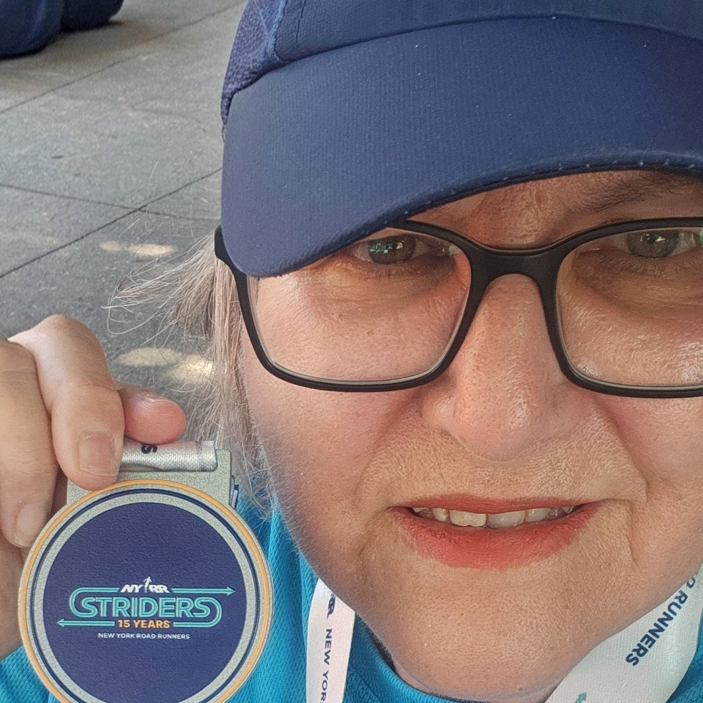 Donna Nerges with Striders medal, cap, and race bib