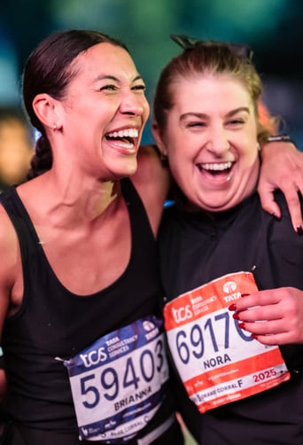 Runner hugging another runner with one arm smiling