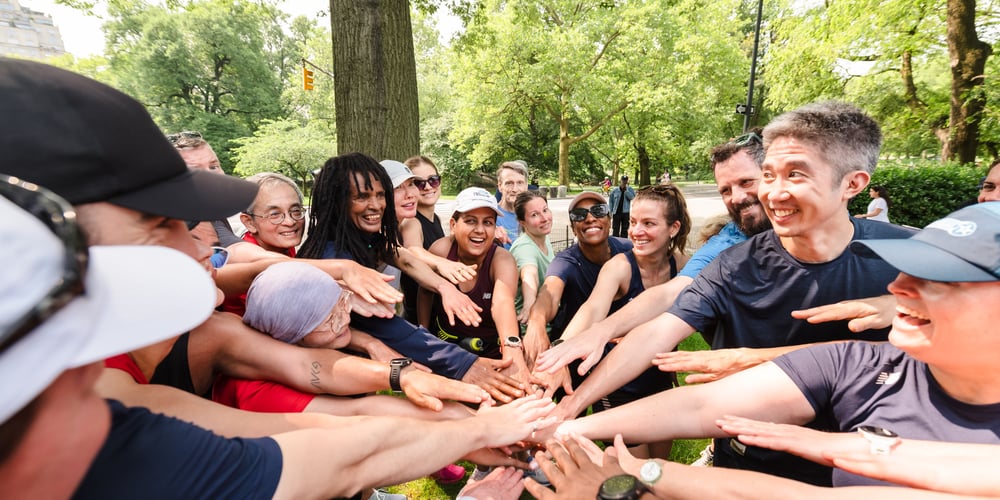 Group Training runners post-workout with hands in center of circle