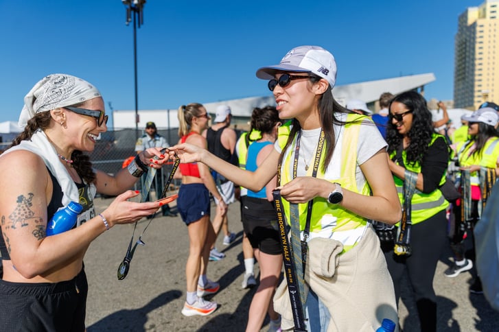 2026 RBC Brooklyn Half finish area volunteer giving medal to finisher