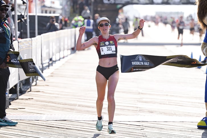 Danica Reinicke breaking the tape to win the nonbinary division of the 2026 RBC Brooklyn Half on the Coney Island boardwalk.