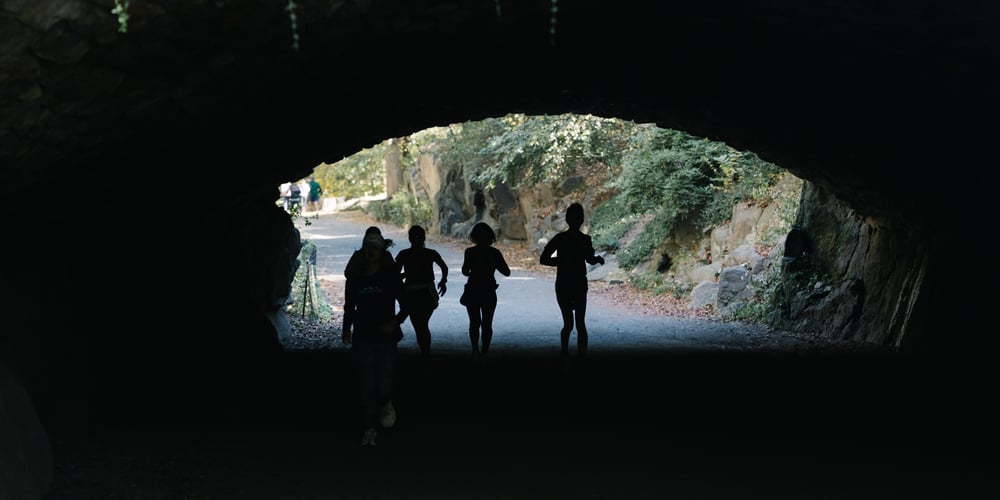 Women runners under a bridge in half light in Central Park in 2025