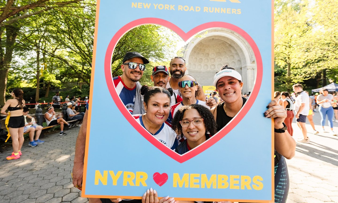 Members with a cut out sign with a heart shape and text that says NYRR loves members