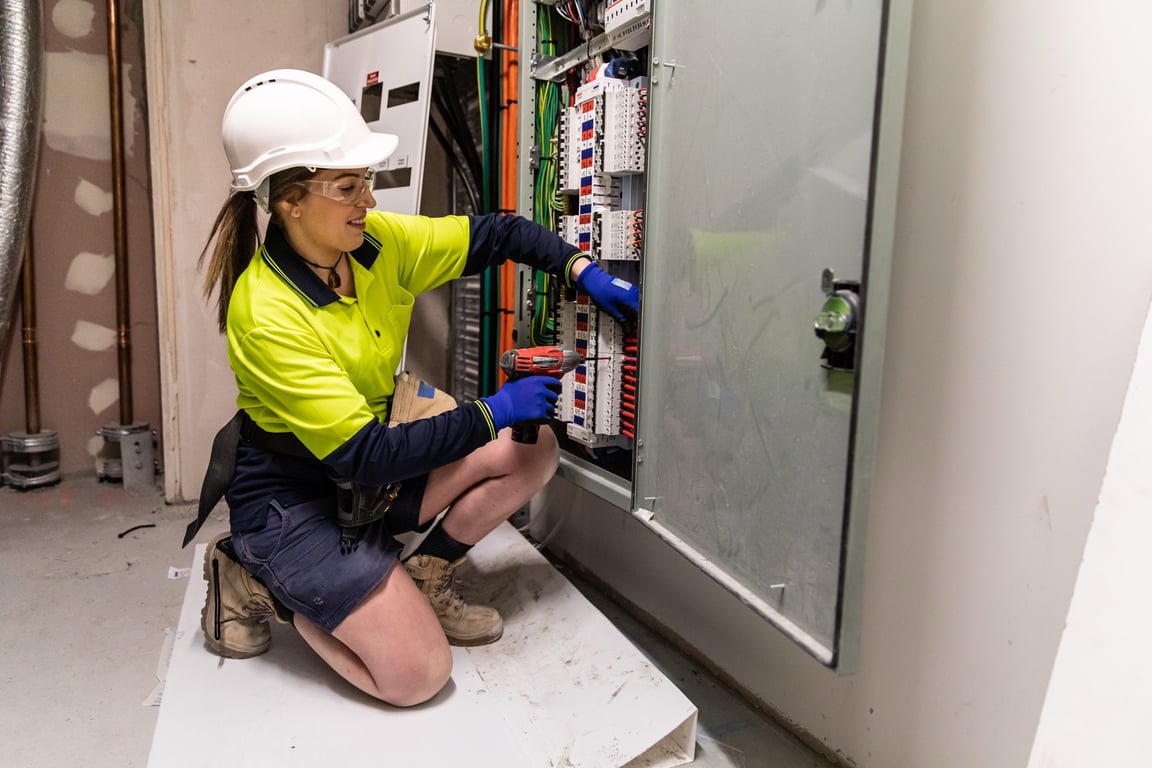 An electrician working on a switchboard while call-outs and enquiries are captured