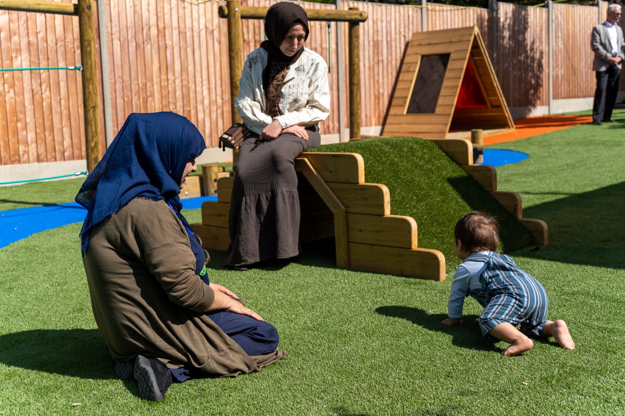 Staff and toddlers exploring the garden climbing frame together