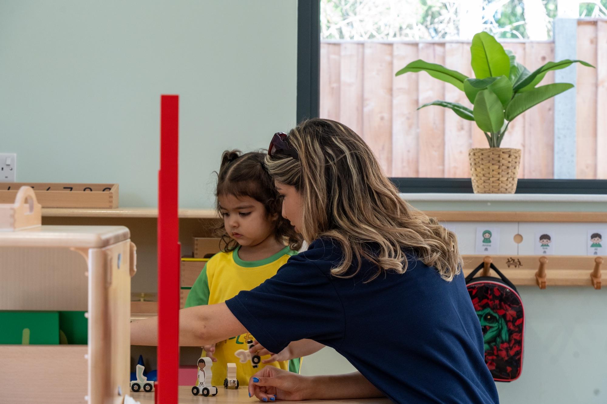 A child and a teacher building a tower together by the window