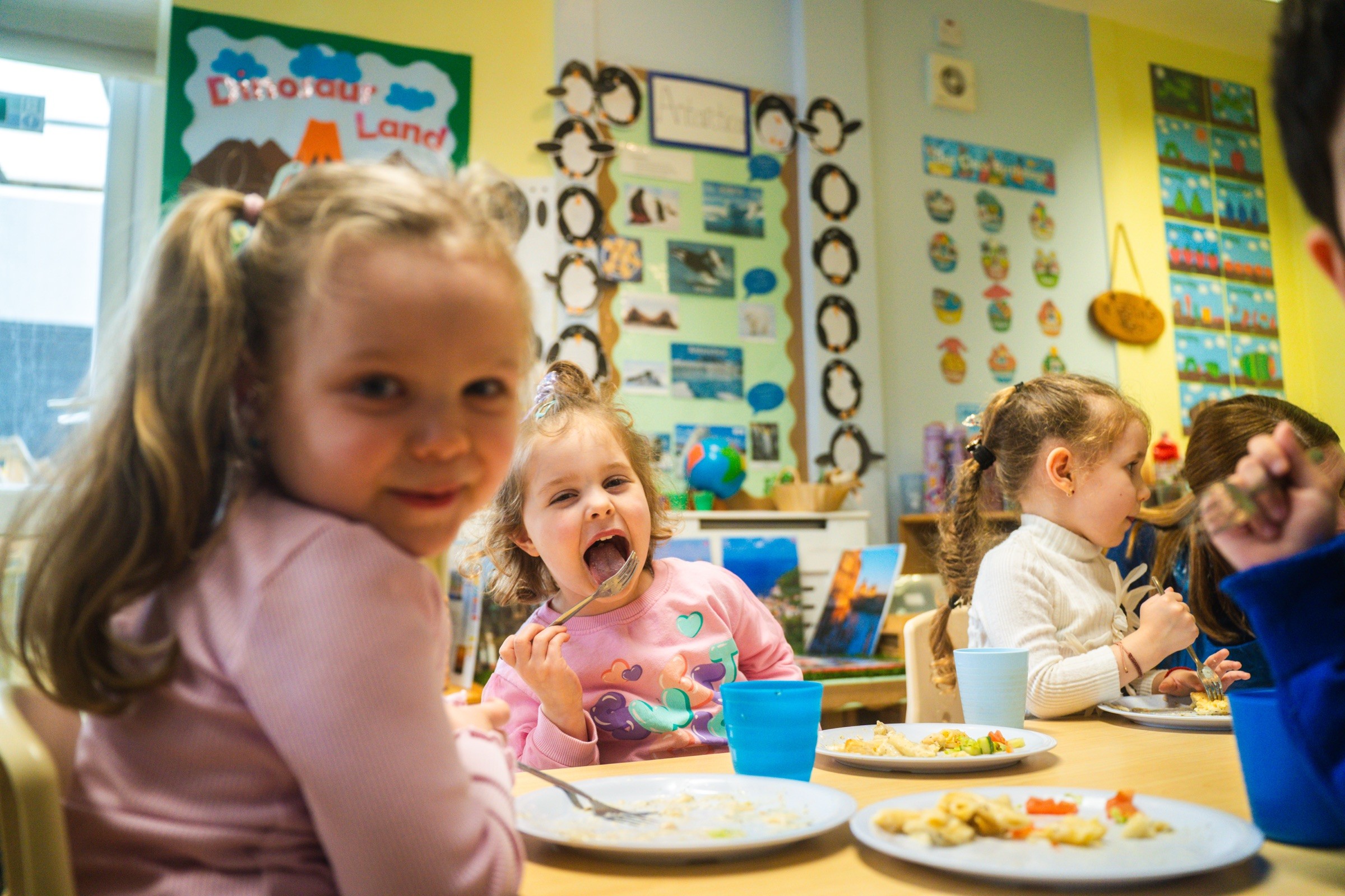 Young children eating a meal together at a nursery table