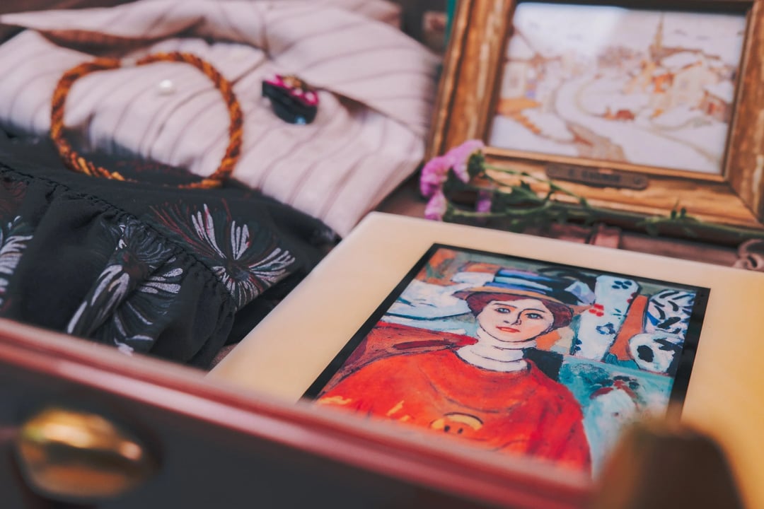 A layout featuring an artwork of a woman in an orange shirt, surrounded by clothing, accessories, and framed pictures.