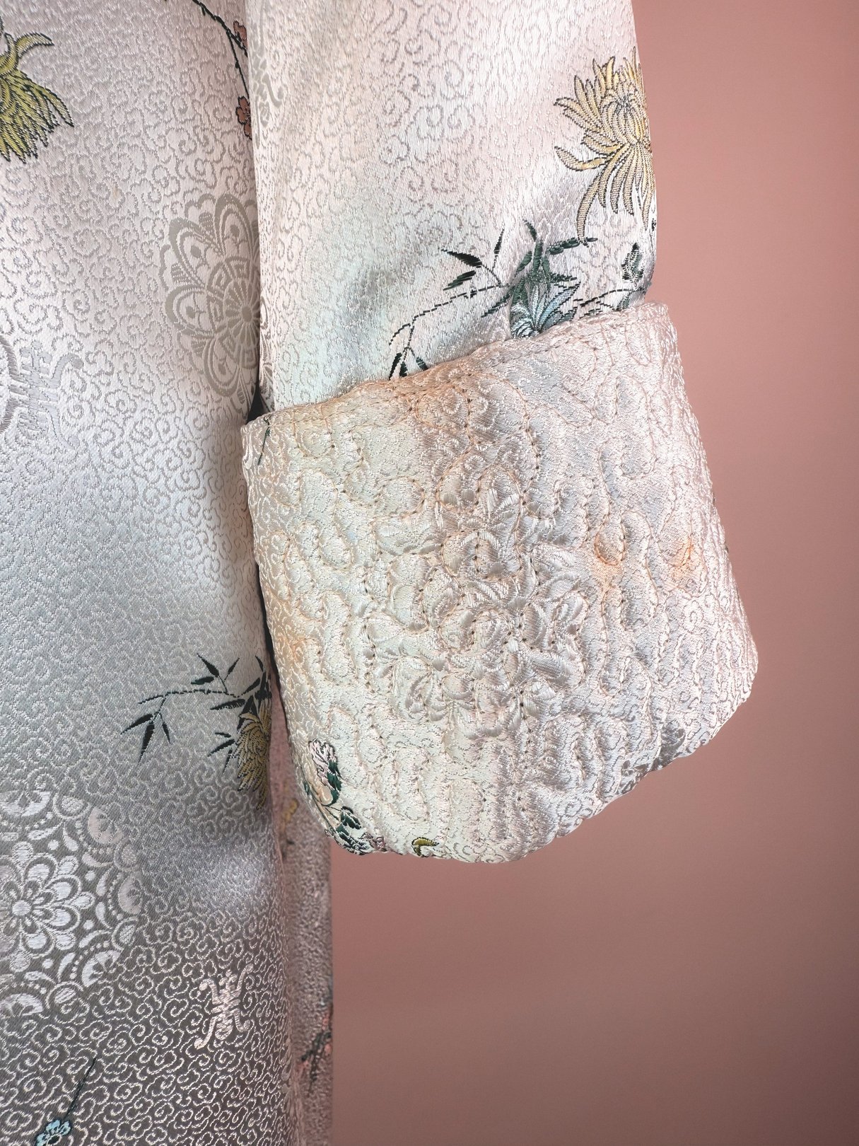 Silver 1970s women's cheongsam coat featuring intricate floral embroidery and a structured collar.