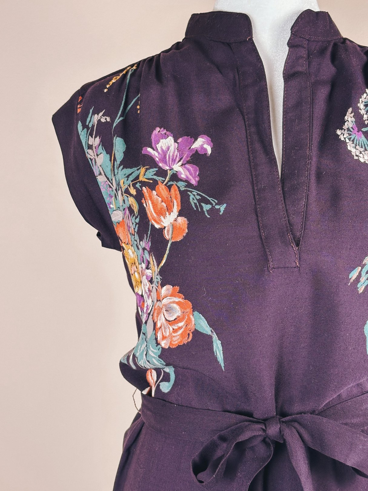 1970s women's dress in purple featuring floral embroidery and a tie waist.