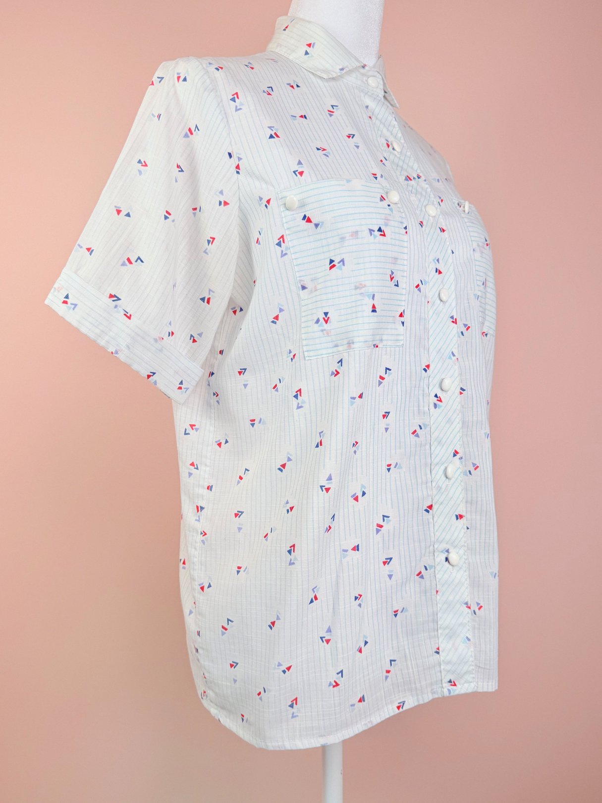 Short-sleeve women's top in blue featuring a playful 1980s print with small triangular patterns.