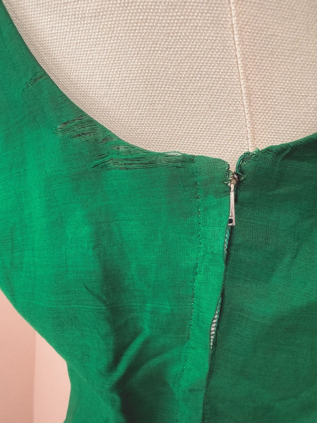 Green 1950s-style dress featuring a starburst design and a zipper closure at the back.