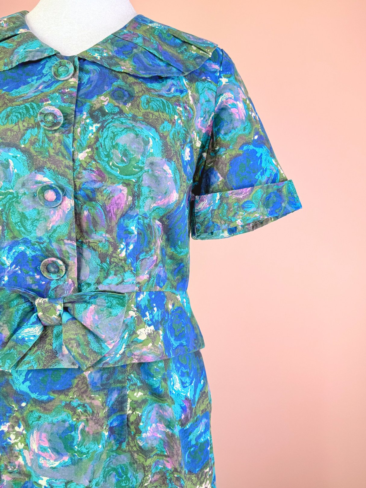 1950s women's coastal flowers skirt set in blue featuring a collared top with buttons and a bow detail at the waist.