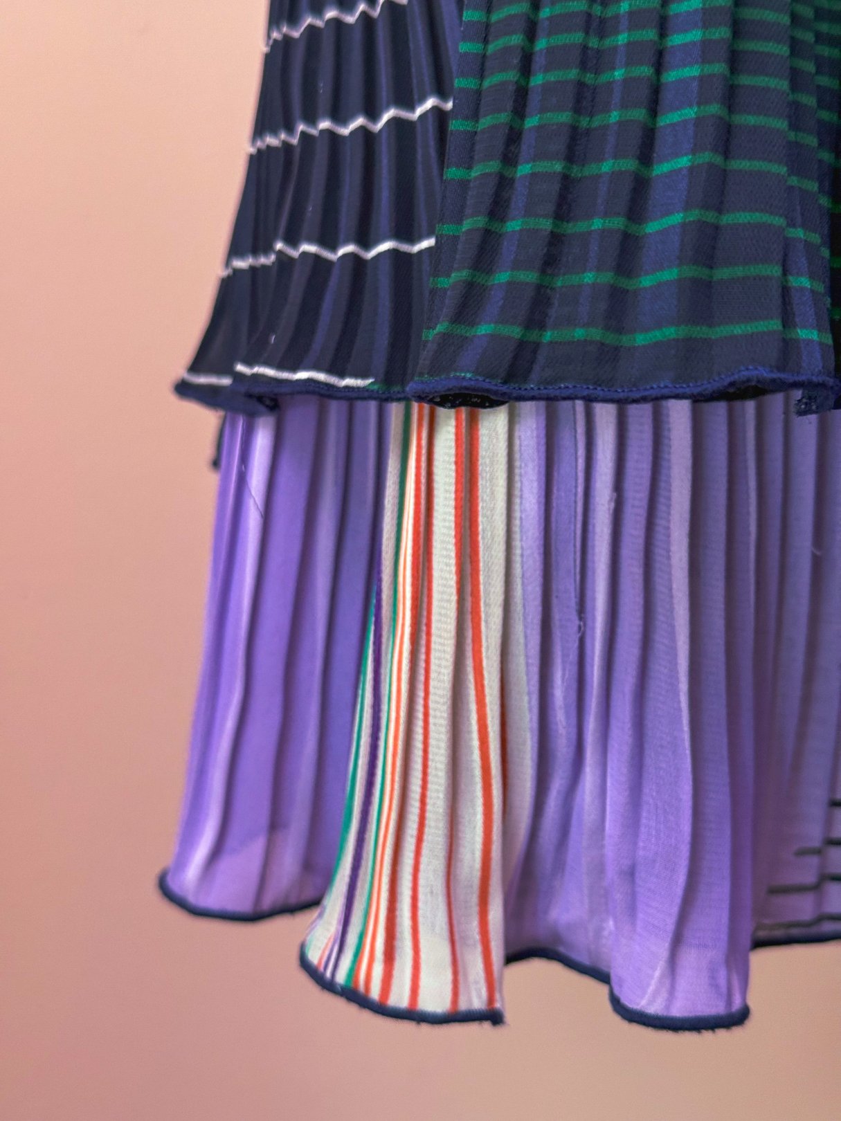 Pleated skirt featuring a mix of green, navy, purple, and striped patterns, styled for women in a 1970s aesthetic.