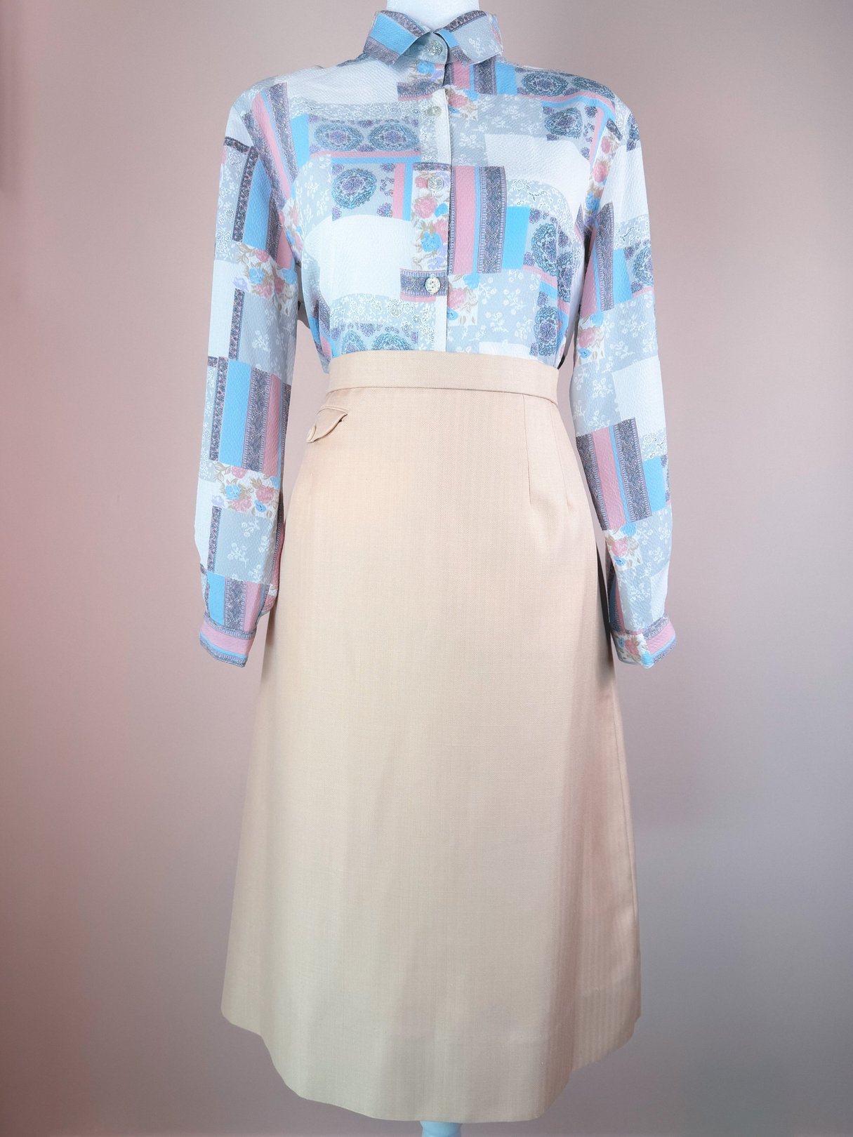 A cream beige 1960s women's skirt displayed with a patterned blouse.