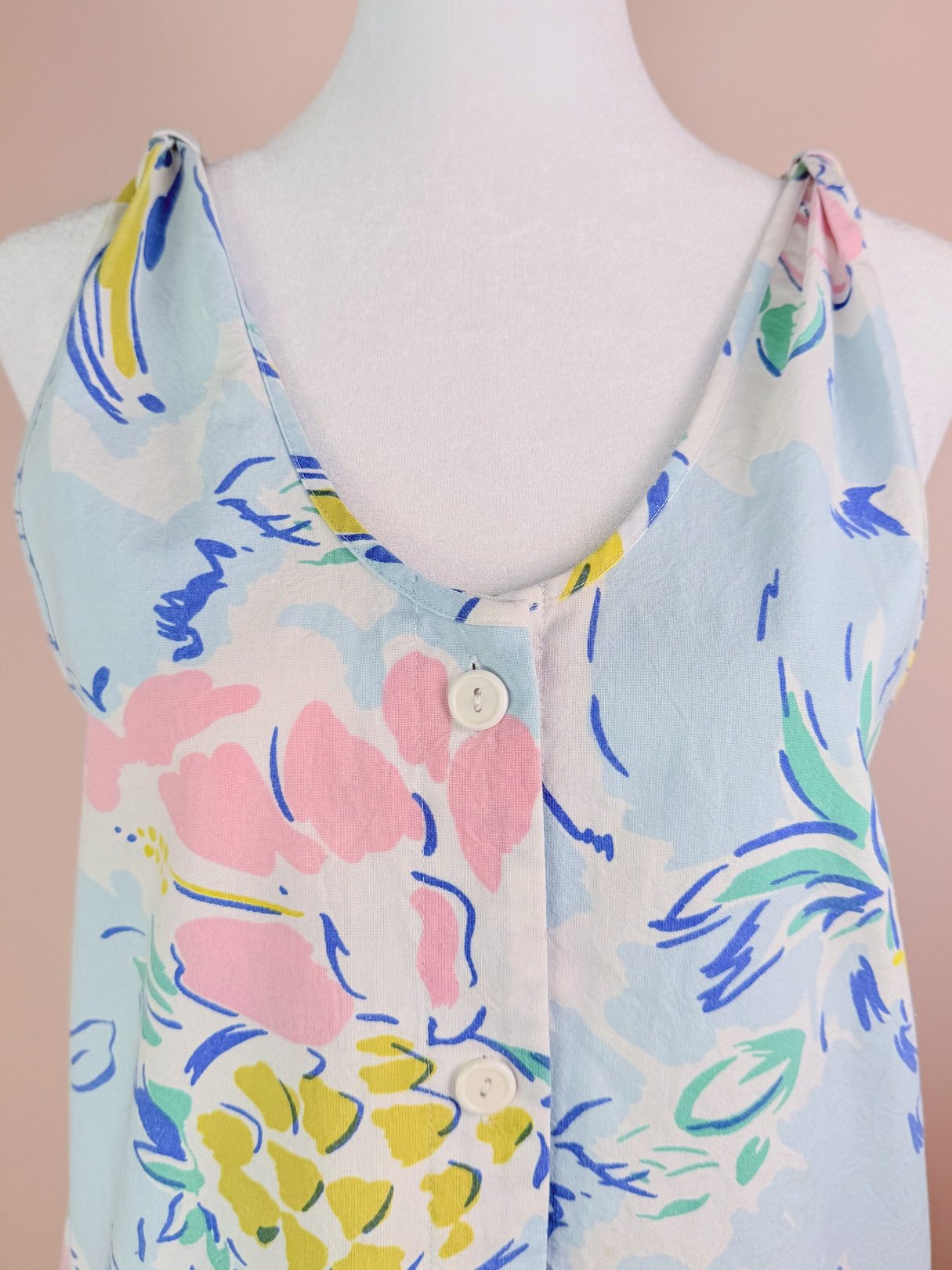 1980s women's blue romper featuring a floral pattern and two buttons at the neckline.