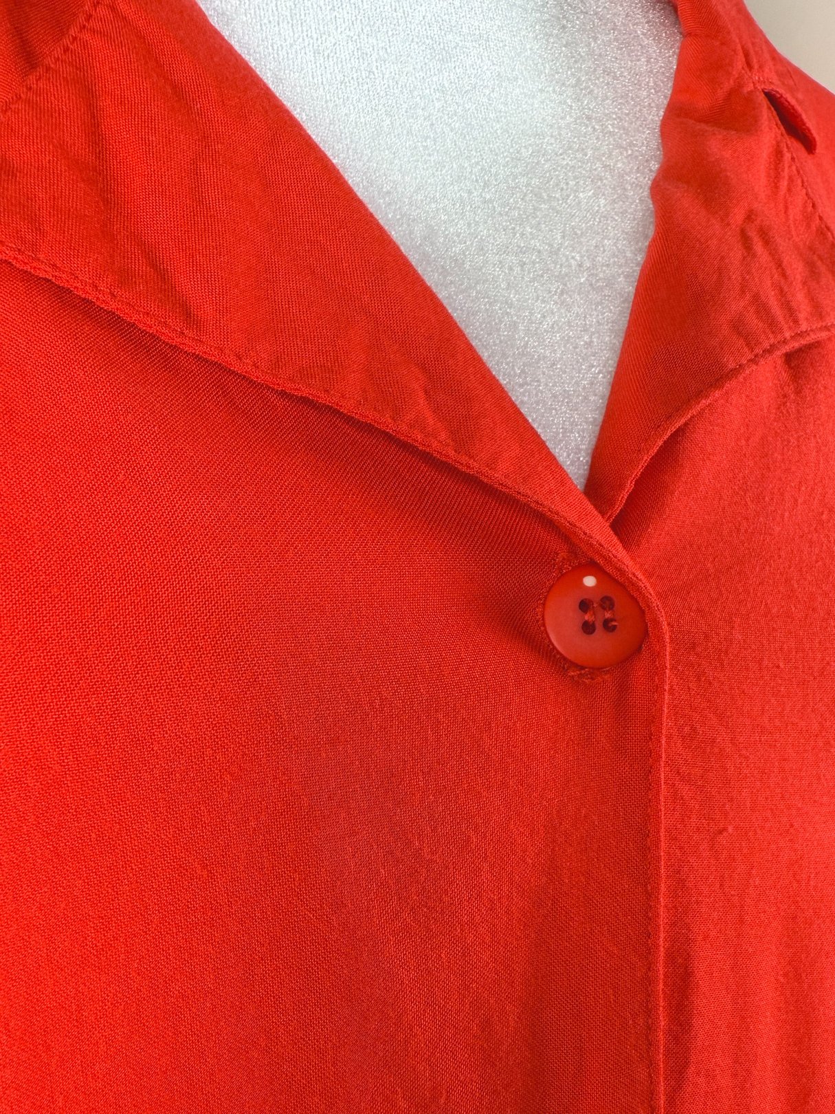 Red 1980s women's top featuring a collar and a front button closure.