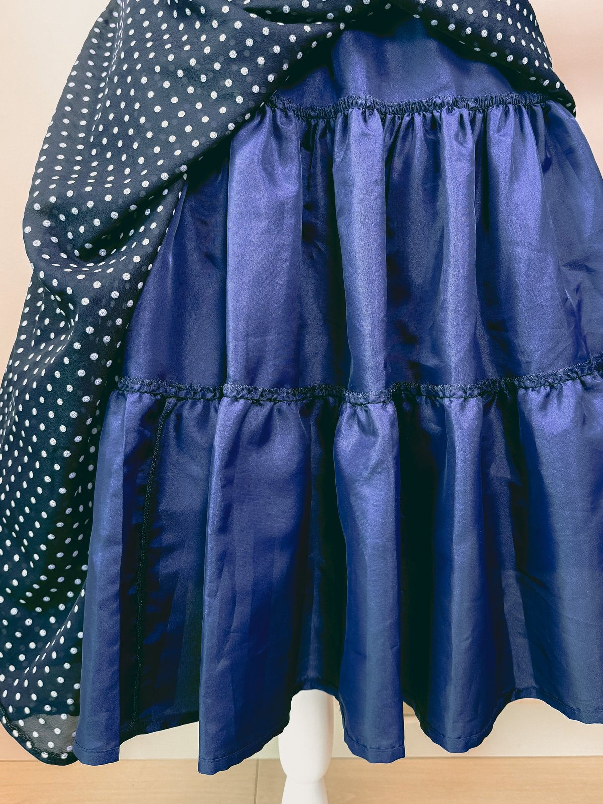 Navy blue 1950s women's dress featuring a polka dot top and a tiered skirt.