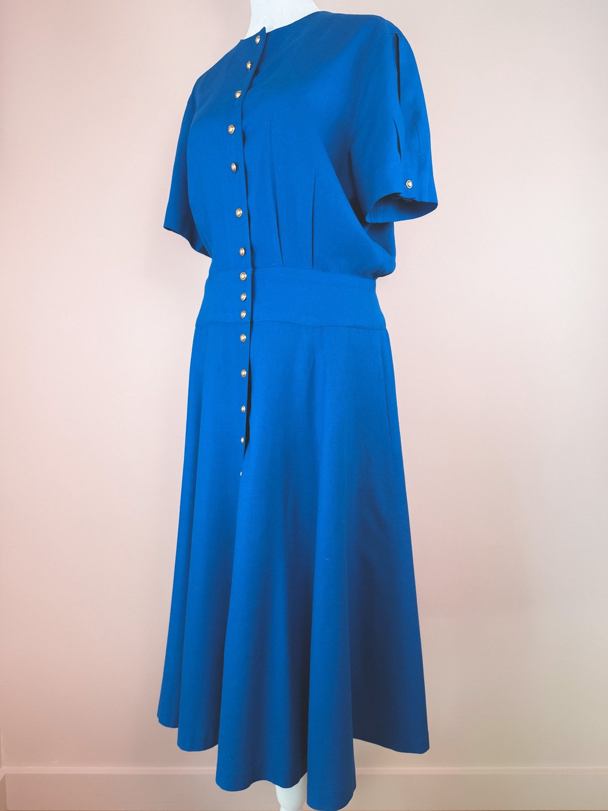 Cerulean blue 1980s women's dress featuring short sleeves, a button front, and a flared skirt.