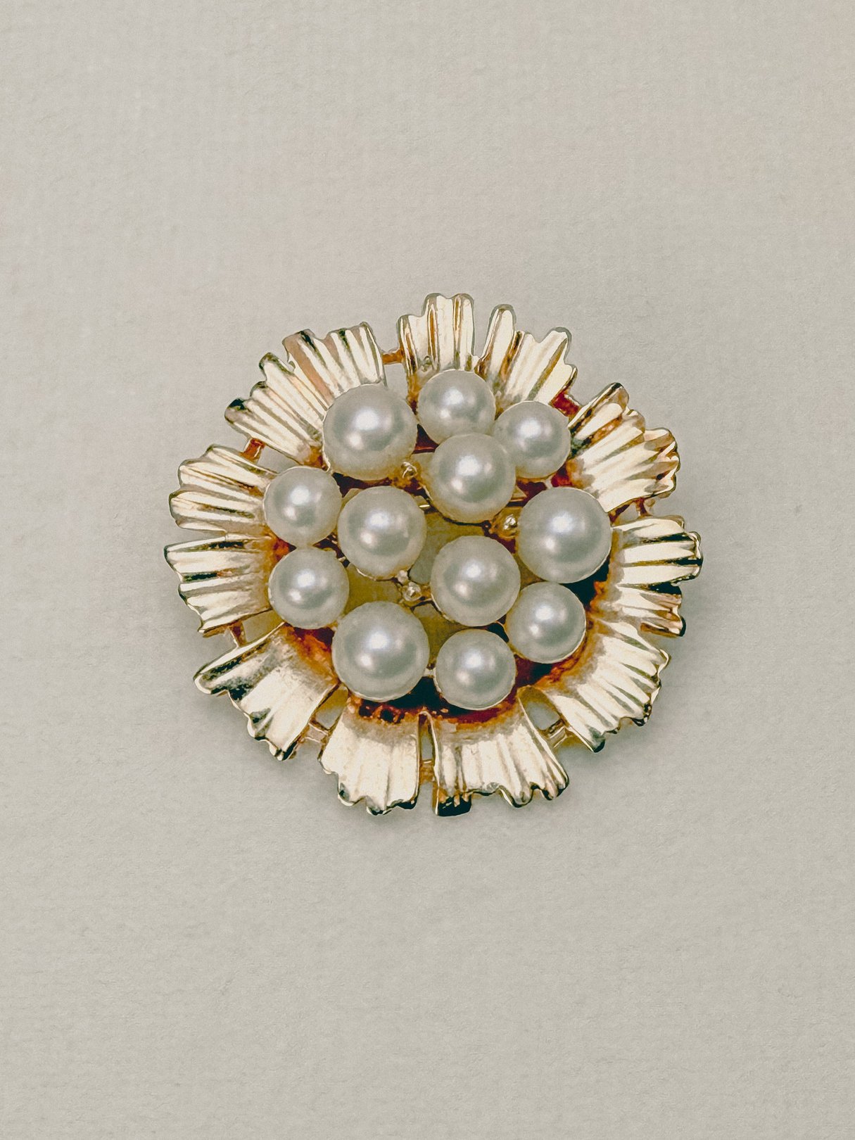 Gold-tone floral brooch from the 1970s adorned with multiple pearls, designed as a women's accessory.