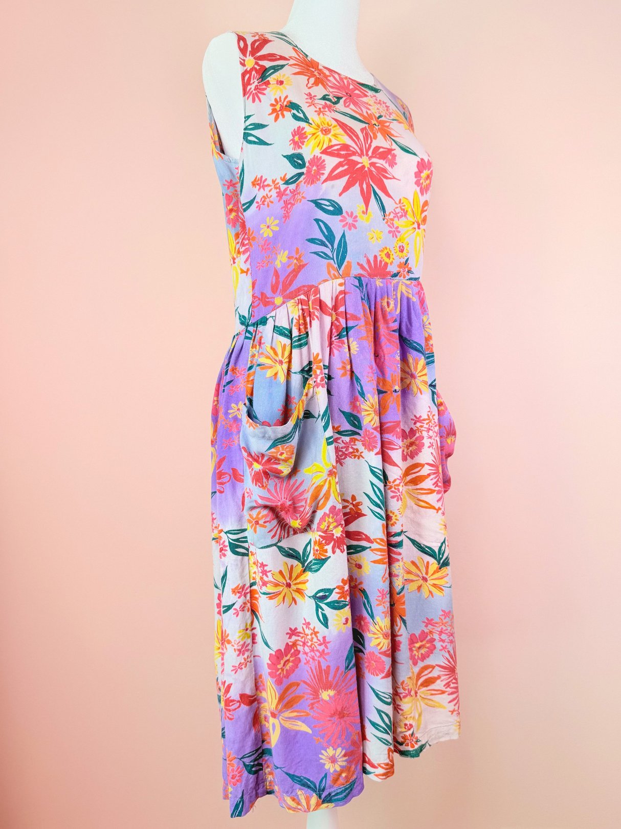 A pink and multicolored floral dress from the 1990s with a one-shoulder design and pockets.