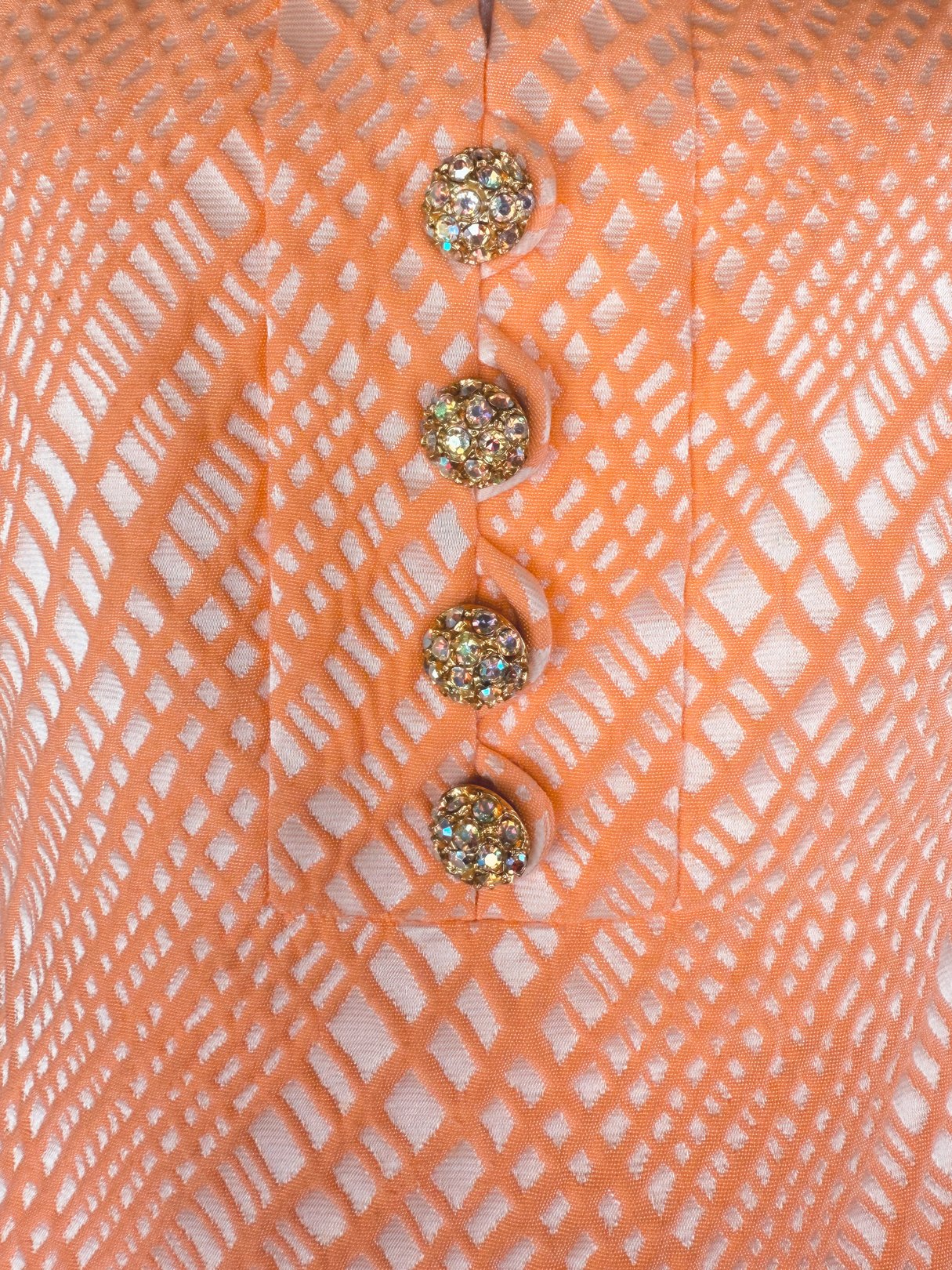 Orange dress featuring a diamond pattern and four embellished buttons, reflective of 1960s fashion.