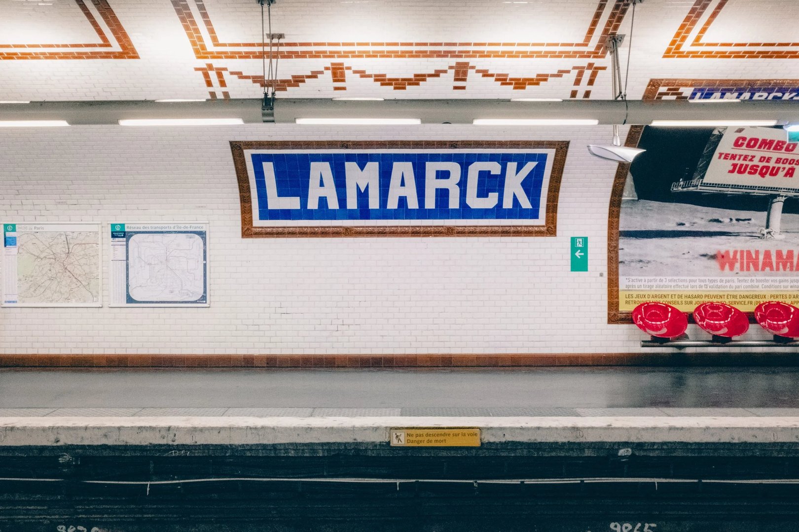 Lamarck subway station sign with tile wall and benches in the background.