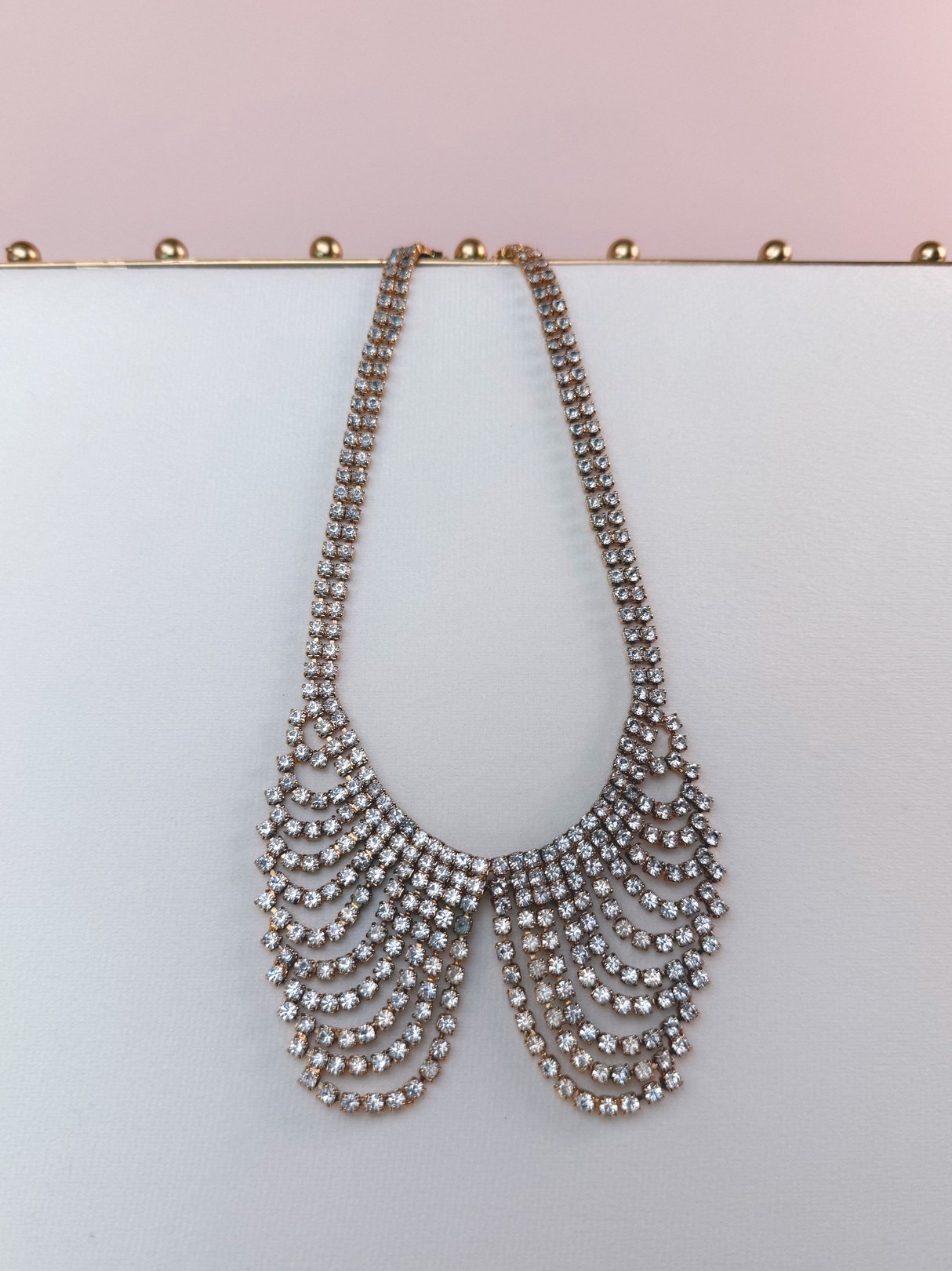 A vintage 1970s gold-tone collar necklace featuring multiple tiers of sparkling clear rhinestones.