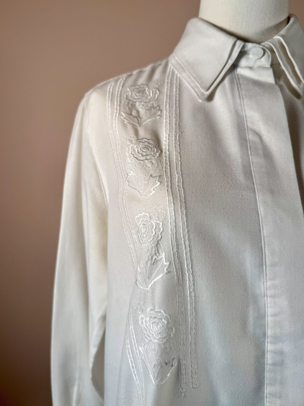 White 1970s women's shirt featuring embroidered floral details along the front.