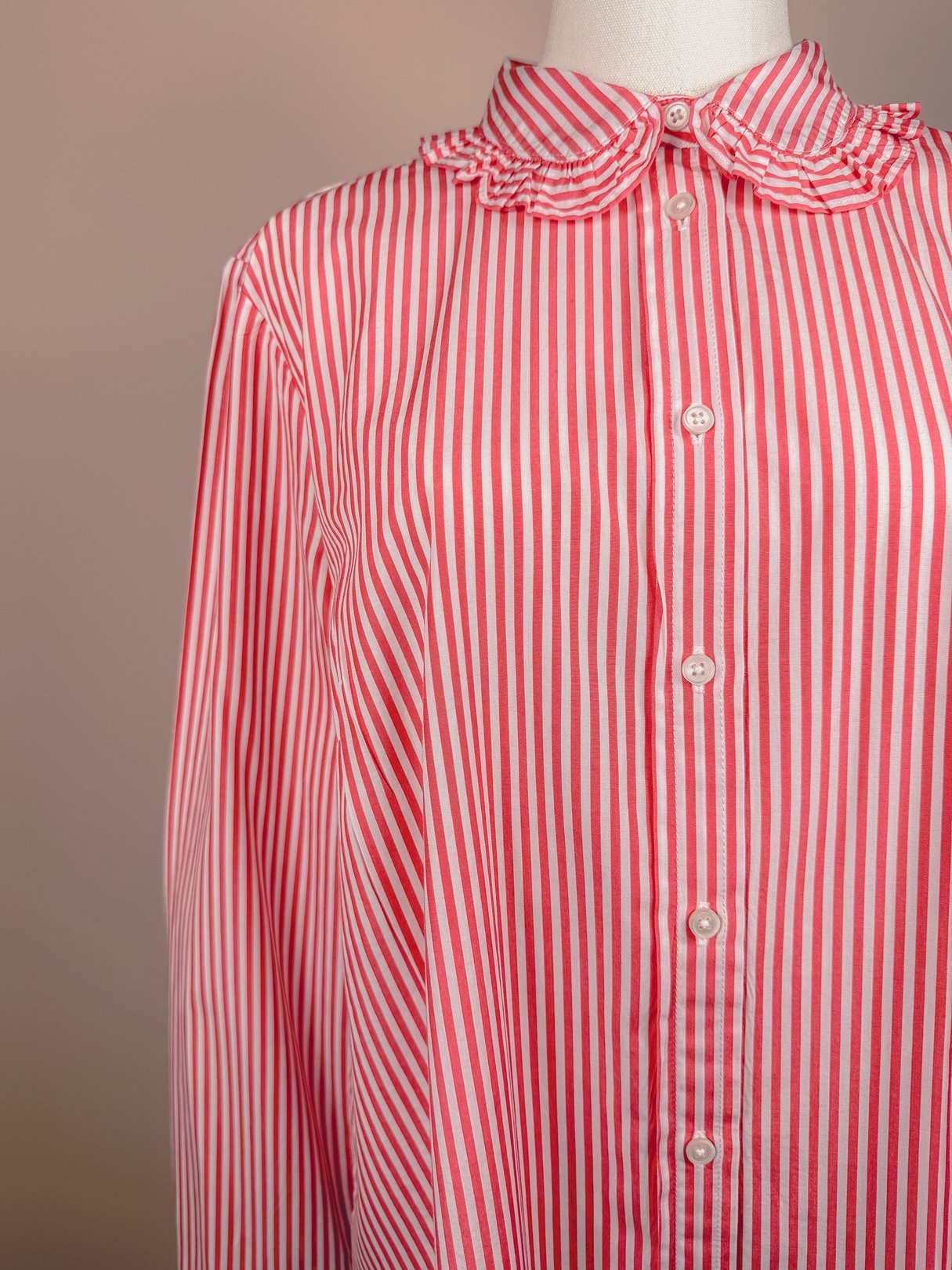 Red and white striped button-down top with a ruffled collar, designed for women and inspired by 1970s fashion.