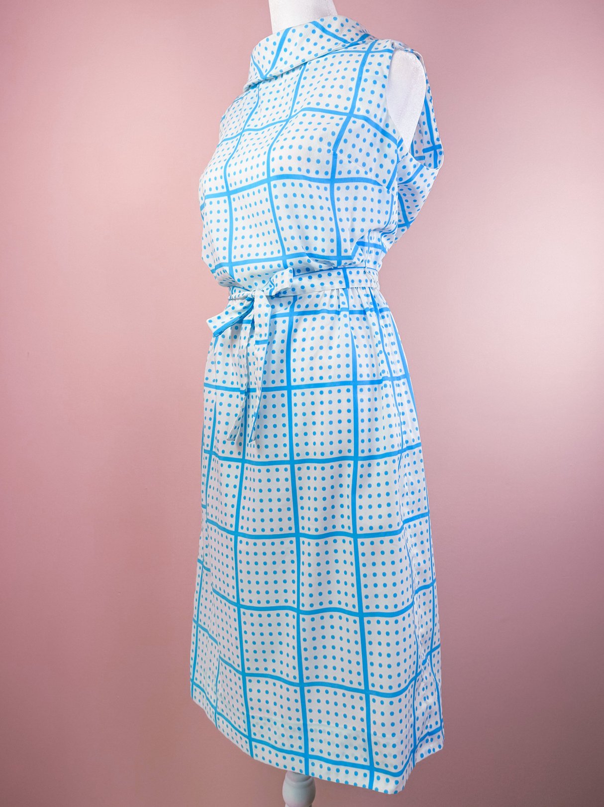 White 1970s women's dress featuring a blue grid pattern and a tie belt.