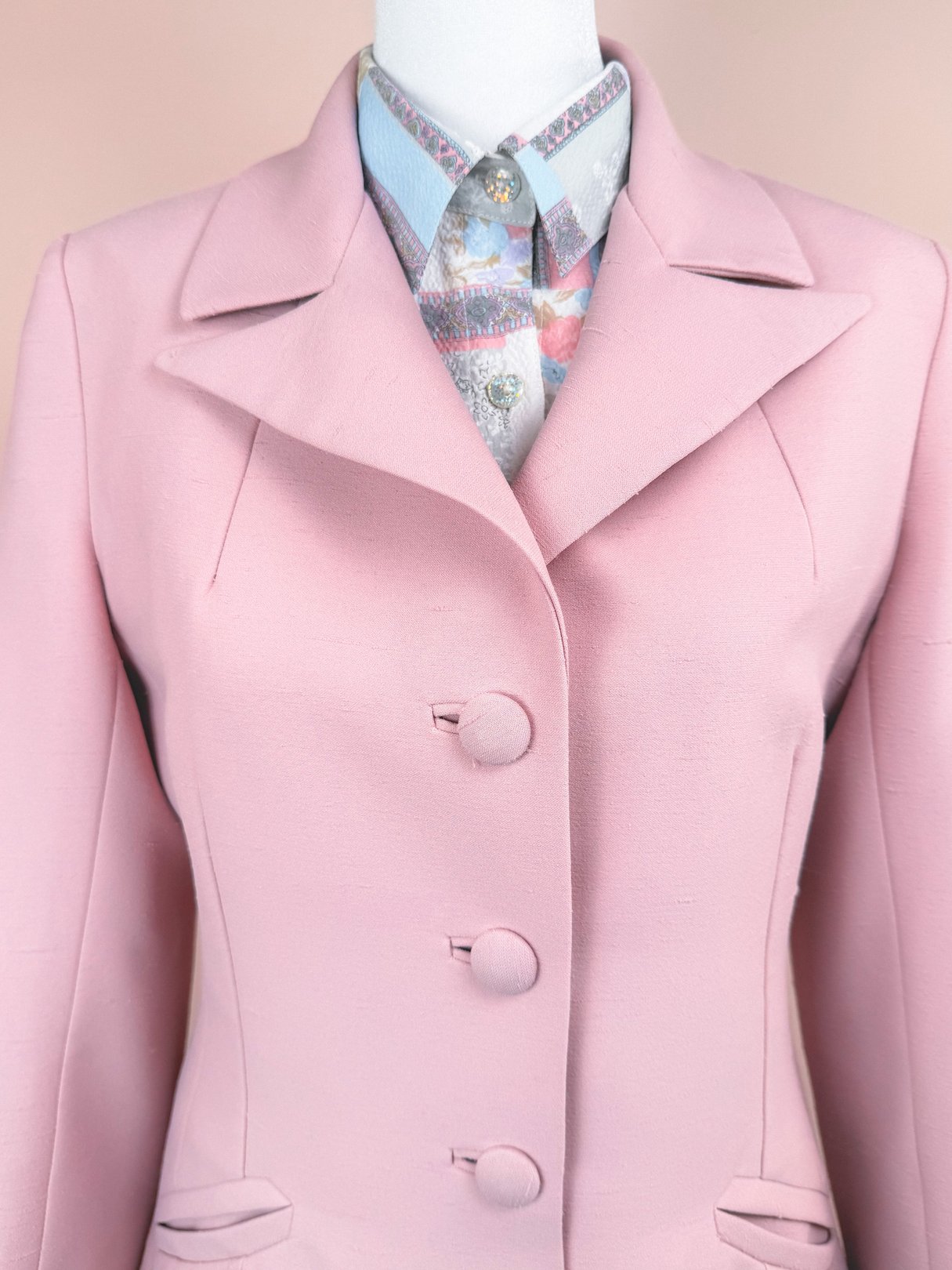 Blush pink three-piece women's suit from Lilli Ann, featuring a tailored blazer and a patterned blouse, dating to the 1970s.